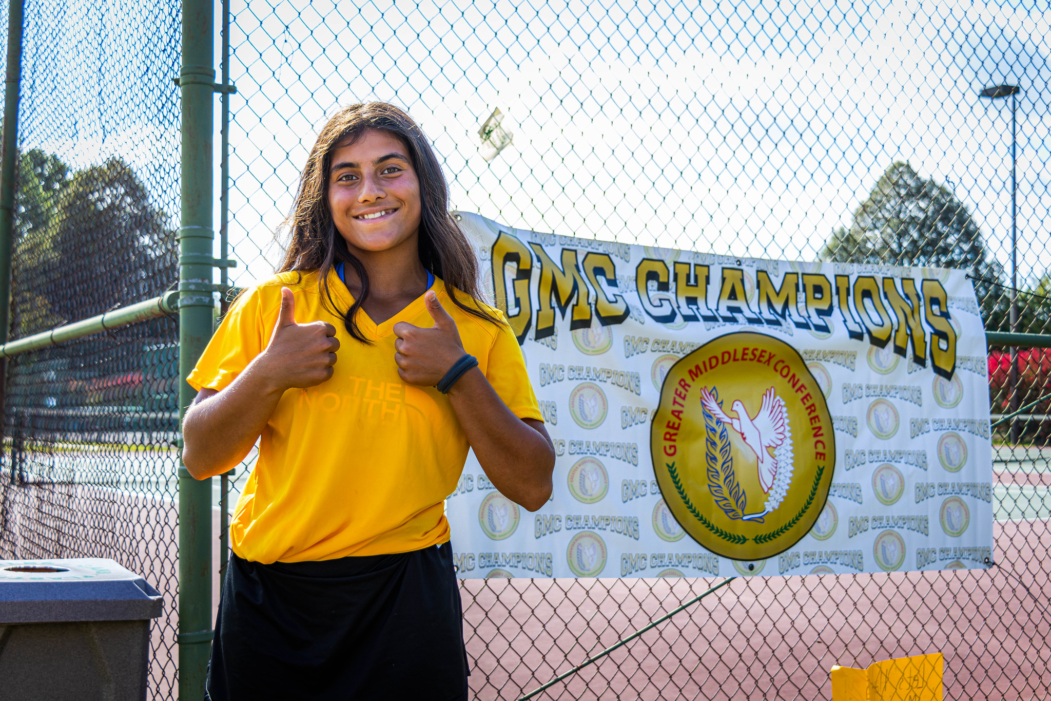 Student smiling in front of athletci banner.